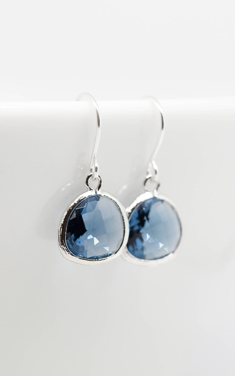 May include: A pair of silver dangle earrings with a round, faceted, light blue gemstone.