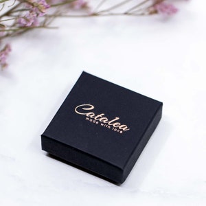 May include: A black square box with the text "Catalea made with love" in gold lettering.
