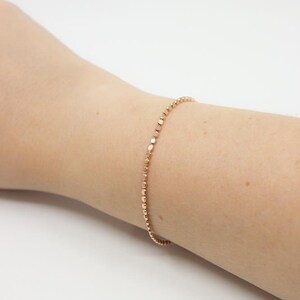 May include: A delicate rose gold bracelet with a chain of small, round beads.