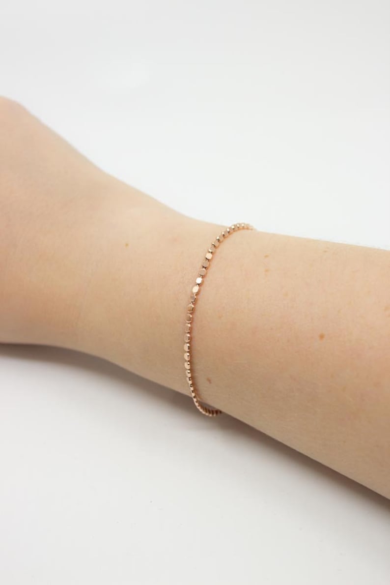 May include: A delicate rose gold bracelet with a chain of small, round beads.