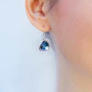 May include: Silver dangle earrings with a teardrop-shaped blue gemstone.