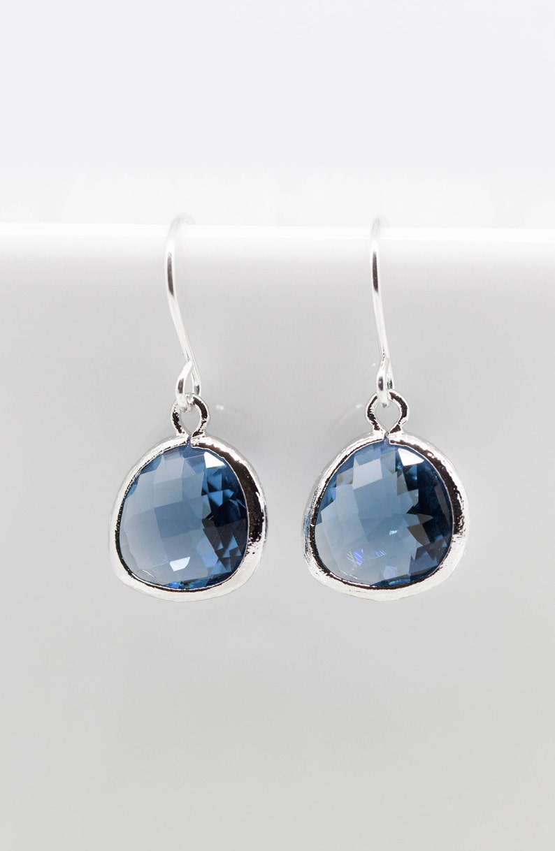 May include: A pair of silver dangle earrings with a blue gemstone in the shape of a teardrop.