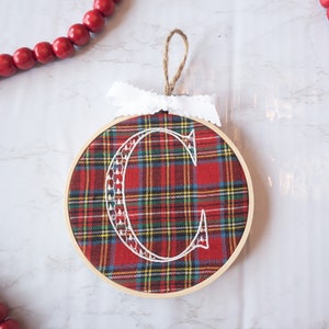 Bestickte Weihnachtszierde, rotes Monogramm und rotes Monogramm im Stickrahmen