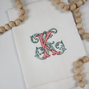 May include: White kitchen towel with a red and green embroidered letter K.