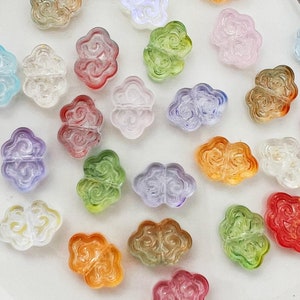 May include: Assortment of colourful glass cloud-shaped beads. The beads are translucent and have a variety of colours, including pink, blue, green, yellow, and orange.