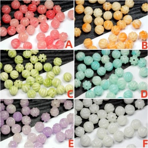 May include: Assortment of six colours of small, round, pumpkin-shaped beads. The beads are made of a smooth, opaque material and have a slightly ribbed texture. The colours are pink, orange, light green, light blue, lavender, and white.