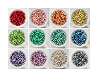 May include: Twelve small bowls each filled with a different color of round, metallic beads. The colors are red, pink, orange, gold, green, teal, blue, purple, lavender, white, cream, and gray.