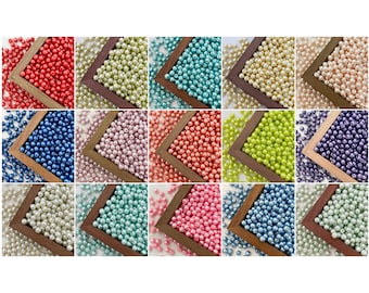 May include: Assortment of pearl beads in various colors, including red, blue, green, pink, and white. The beads are displayed in small wooden frames.