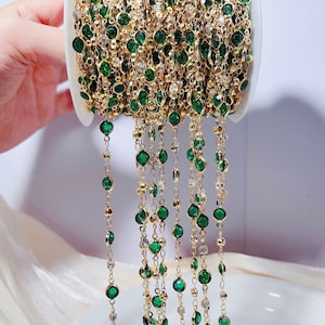 May include: A spool of gold chain with emerald green beads. The chain is strung with small, round beads and is ideal for jewellery making.