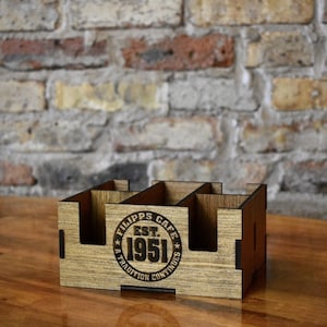 May include: Wooden cutlery holder with four compartments. The holder is engraved with the text "Filipps Cafe Est. 1951 A Tradition Continues".