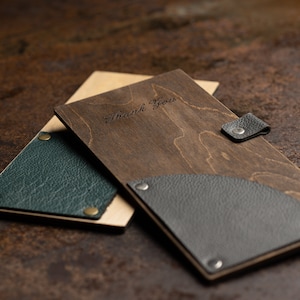 May include: Two wooden menu covers with leather accents. One cover is dark brown with a black leather flap and the text "Thank You" engraved on the front. The other cover is light brown with a green leather flap.