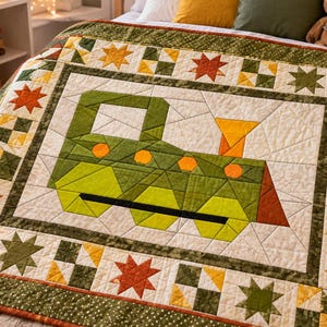 May include: A patchwork quilt featuring a central green train engine design with orange circular accents and a yellow smokestack. The border consists of alternating star patterns and small squares in shades of green, yellow, and orange on a cream background.