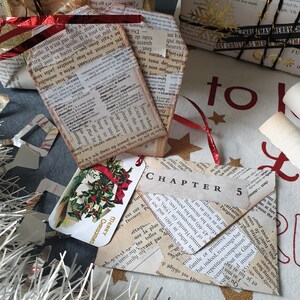 May include: Christmas-themed gift tags and wrapped presents. The gifts are wrapped in paper made from book pages, with red ribbon and gold accents. One tag reads "Merry Christmas" and another says "Chapter 5".