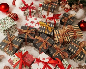May include: A collection of small, wrapped gift boxes with various patterns, including stars, trees, and floral designs. Each box is adorned with a ribbon, some red and some gold. Red ornaments and miniature Christmas trees are scattered around the gifts.