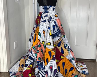 May include: A black sleeveless top with a V-neckline and a white and colorful patterned skirt. The skirt has a high waist and a flowing silhouette.