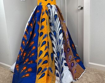May include: A long, flowing skirt with a peacock feather print in shades of blue, yellow, white, and brown. The skirt has a wide waistband and is made of a lightweight fabric.