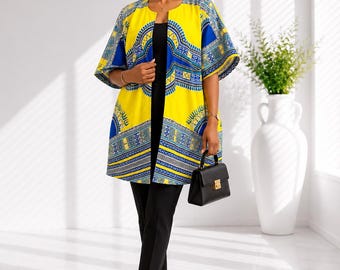 May include: A bright yellow open-front jacket featuring a vibrant blue and white geometric pattern. The jacket has wide, elbow-length sleeves and a straight hemline. It is worn over a simple black top and black trousers, paired with black heels.
