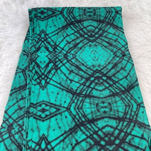 Könnte beinhalten: Grün-schwarze Leggings mit geometrischem Muster. Das Muster besteht aus kleinen schwarzen Punkten und Linien, die ein netzartiges Design bilden.