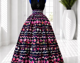 May include: A floor-length dress featuring a sleeveless black bodice with a V-neckline and a high-waisted, full-length skirt. The skirt is navy blue with horizontal rows of pink, white, and green circular and zigzag geometric patterns.