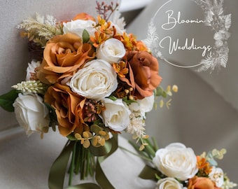 May include: A set of three floral arrangements featuring a bouquet, a smaller bouquet, and a boutonniere. The flowers are a mix of white and orange roses with greenery. The text "Bloomin' Weddings" is visible in the background.