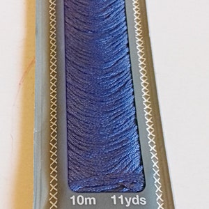 Puede incluir: Una bobina de hilo de bordar Madeira Moulin&eacute; de color morado claro. La etiqueta indica "2702 22" y especifica que el hilo es 100% algod&oacute;n, mercerizado y resistente a la decoloraci&oacute;n. La bobina contiene 10 metros (11 yardas) de hilo.