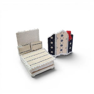 May include: A miniature bed with a cream-colored quilt and two matching pillows, each featuring thin horizontal black lines and white lace trim. Beside the bed stands a three-panel folding screen with navy blue and cream floral patterns.