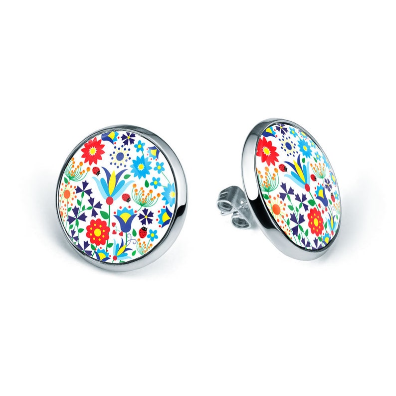 May include: A pair of silver stud earrings with a round white background and a colorful floral pattern. The pattern includes red, yellow, blue, green, and orange flowers, leaves, and ladybugs.