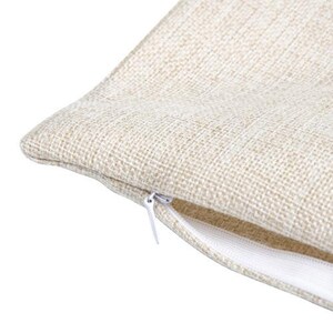 May include: Close-up of a beige linen pillow cover with a white zipper. The zipper is partially open, revealing the inside of the pillow cover.