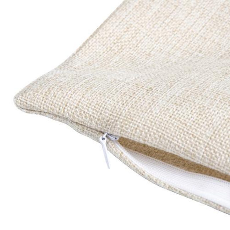 May include: Close-up of a beige linen pillow cover with a white zipper. The zipper is partially open, revealing the inside of the pillow cover.