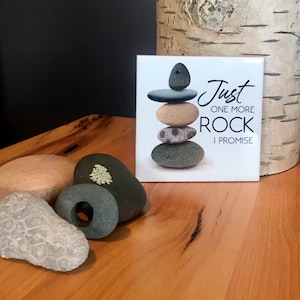 May include: White ceramic tile with a black and white graphic of a stack of rocks. The text "Just one more rock I promise" is printed on the tile.