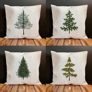 May include: Four white pillow covers with a green pine tree design. The trees are different shades of green and have a rustic look.