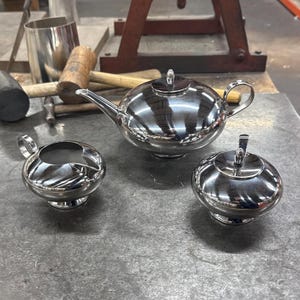 Puede incluir: Un juego de tres tazas de cerámica con un acabado moteado y mate. Las tazas son de color crema, gris claro y gris oscuro. Cada taza tiene un diseño simple y minimalista, ideal para café o té.