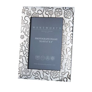 May include: Silver photo frame with a floral design. The frame is made by Wentworth Pewter and is designed to fit a 6x4 inch photo. The frame has the text "Wentworth Pewter" and "Photograph Frame to fit 6" x 4" printed on it.