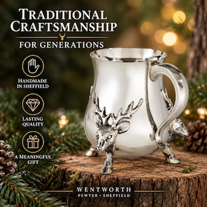 May include: A silver-colored pewter mug featuring three-dimensional stag head accents and curved feet. The mug includes text reading TRADITIONAL CRAFTSMANSHIP FOR GENERATIONS, HANDMADE IN SHEFFIELD, LASTING QUALITY, A MEANINGFUL GIFT, and WENTWORTH PEWTER SHEFFIELD.