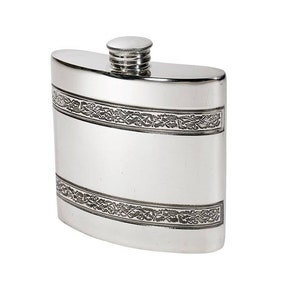 Può includere: Una fiaschetta in metallo color argento lucido di forma rettangolare curva con tappo a vite. La fiaschetta presenta due fasce orizzontali con intricati motivi a intreccio in rilievo che avvolgono le sezioni superiore e inferiore del corpo.