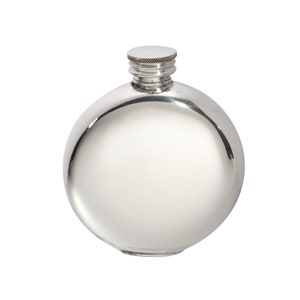 May include: A round, polished silver-colored metal flask with a smooth, reflective surface. The container features a short, threaded neck topped with a matching circular screw-on cap that has a textured, ridged edge for grip and easy opening.