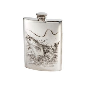 May include: A silver-coloured metal flask featuring a detailed embossed scene of a fish jumping out of water with a fishing line visible above. The flask has a curved rectangular shape and a small, circular screw-top cap at the centre top.