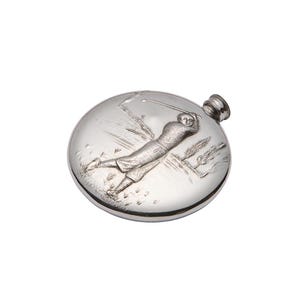Op de afbeelding: Een ronde, zilverkleurige metalen heupfles met een reliëf van een golfer tijdens een swing op een golfbaan. De fles heeft een glad, reflecterend oppervlak en een kleine schroefdop aan de rechterbovenkant van de ronde behuizing.