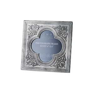 Op de afbeelding: Een zilverkleurig metalen fotolijst met een sierlijk ontwerp. De lijst is ontworpen om een foto van 10,16 x 10,16 cm te passen. De lijst heeft de tekst "TWO FLWYER" en "PHOTOGRAPH FRAME TO FIT 4" X 4"" erop.