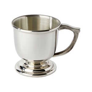 May include: A polished silver-toned metal mug featuring a smooth, rounded bowl shape, a flared rim, and a sturdy, curved handle. The vessel is supported by a wide, tiered circular pedestal base, creating a classic silhouette with a reflective finish.