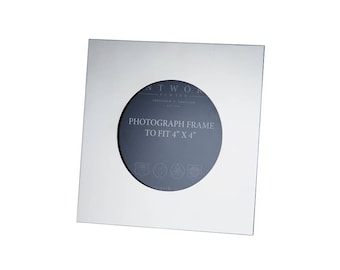 Puede incluir: Un marco de fotos cuadrado de metal color plata con un recorte central circular. El inserto oscuro presenta el texto Wentworth Pewter Sheffield England, Photograph frame to fit 4" x 4" y cuatro pequeños iconos de emblemas circulares en la parte inferior.