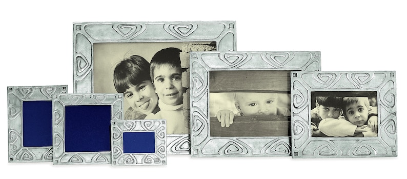 May include: Set of five silver-toned picture frames with ornate designs. The frames are arranged in a row, with the largest frame in the center and the smallest frame on the left. Each frame features a different design, but all have a similar swirling pattern. The frames are empty, but there are images of children in the background.