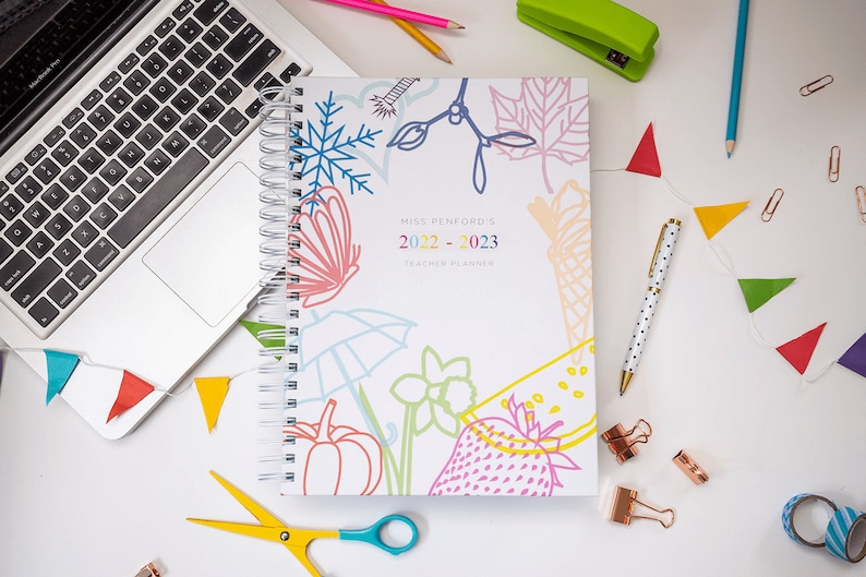 White wire bound Teacher planner with various icon drawings, strawberry, flower, butterfly, snowflake, ice cream and a snowflake. 2 sizes, A4 & A5, choice of colour in the wires and  ribbons.