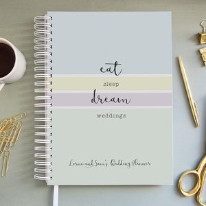 Może przedstawiać: Planer ślubny w jasnoniebieskie, ż&oacute;łte i fioletowe paski z tekstem "eat sleep dream weddings" i "Lorna and Sean's Wedding Planner".