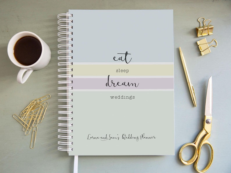 Może przedstawiać: Planer ślubny w jasnoniebieskie, ż&oacute;łte i fioletowe paski z tekstem "eat sleep dream weddings" i "Lorna and Sean's Wedding Planner".