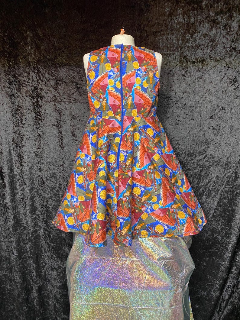 May include: A sleeveless, knee-length dress with a vibrant, patterned design. The dress features a blue zipper down the back and a full skirt. The pattern includes figures, wings, and yellow circles on a blue, orange, and red background.