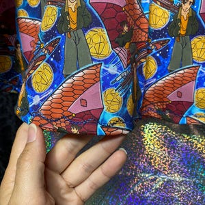 May include: A colorful fabric featuring a repeating pattern of a cartoon character in a green jacket and yellow shirt, set against a blue starry background. The design includes orange and pink airships and yellow geometric shapes.