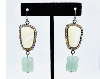 May include: A pair of dangle earrings with a white shell-like stone surrounded by rhinestones and a light blue square stone hanging below.