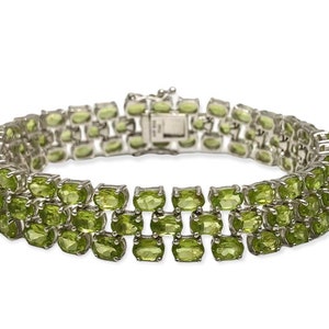 May include: A silver bracelet with a double row of green peridot gemstones. The bracelet has a secure clasp.