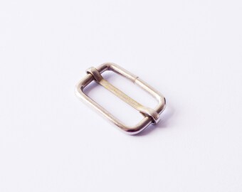 May include: A silver metal buckle with a rectangular shape and a smooth finish.